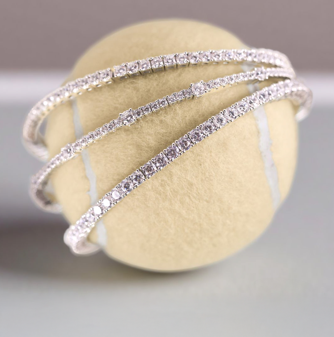 Lafonn sterling silver diamond simulant tennis bracelets wrapped around a tennis ball, showcasing the brand’s elegant sparkle and craftsmanship in a modern jewelry display.