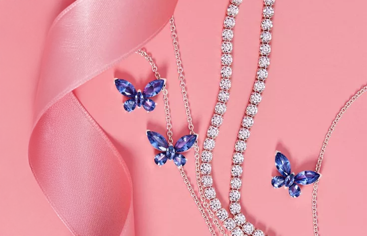 Pandora Timeless Collection featuring blue crystal butterfly earrings and necklace with sparkling tennis chains, styled on a pink background with satin ribbon — elegant, radiant jewelry perfect for gifting and everyday luxury.
